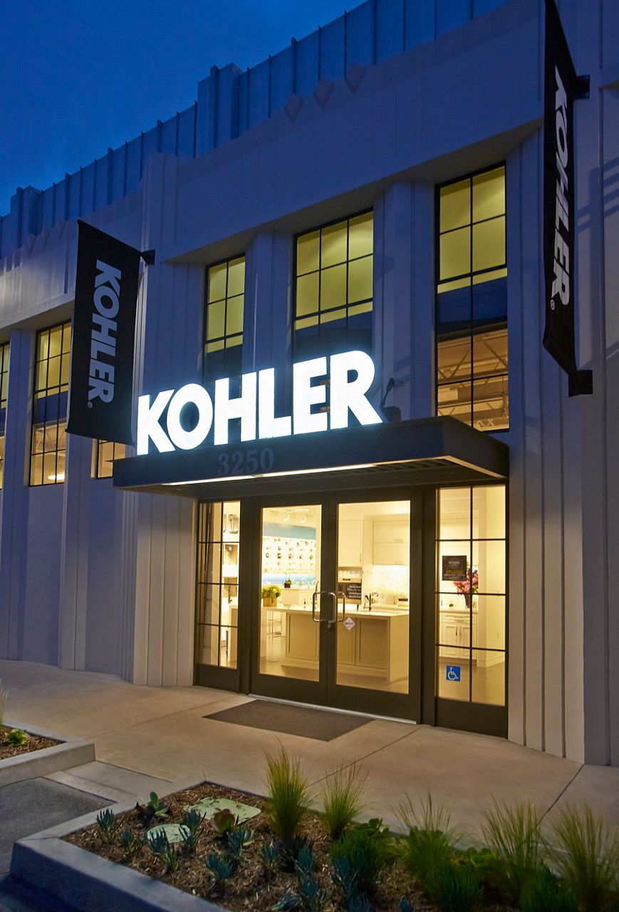 Storefront view of the Kohler building with lit signage at night.