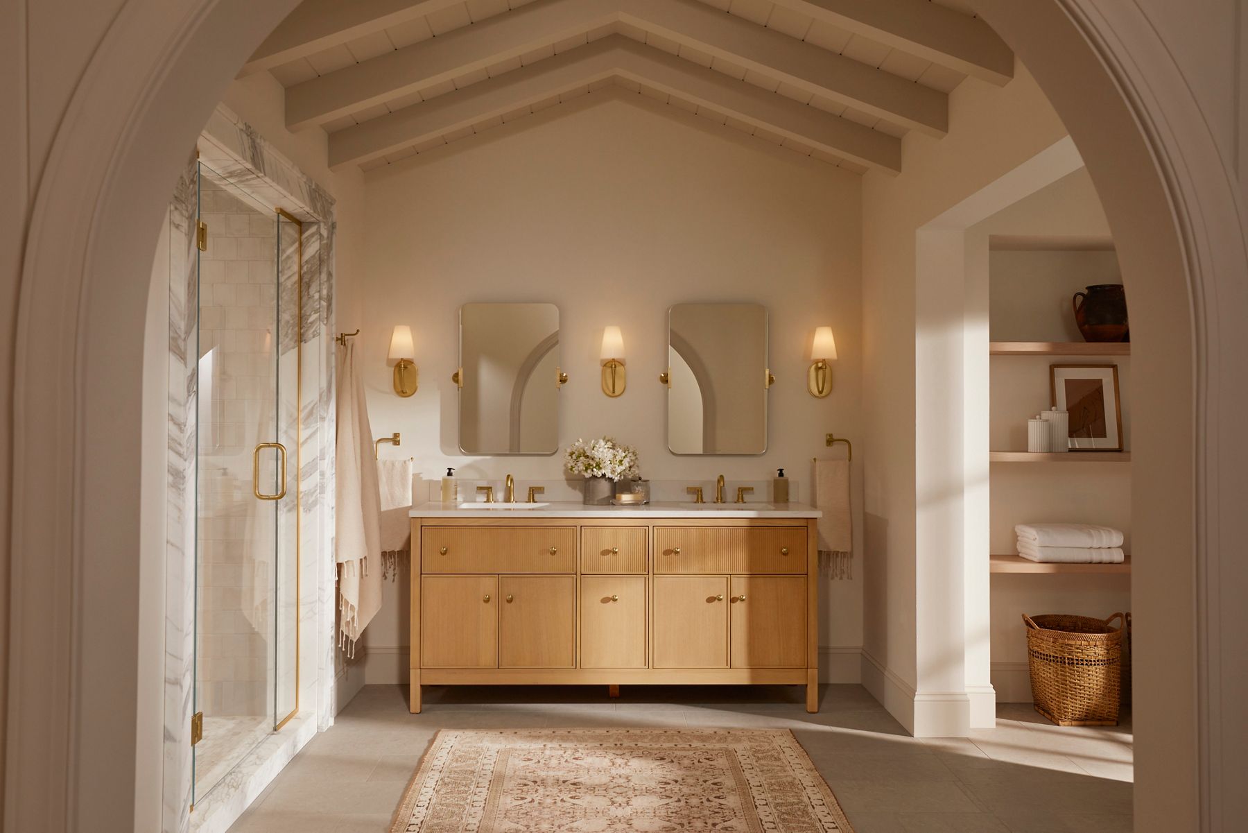 A neutral tone bathroom of beige and light colored wood with a double vanity in the center designed by Shea McGee.
