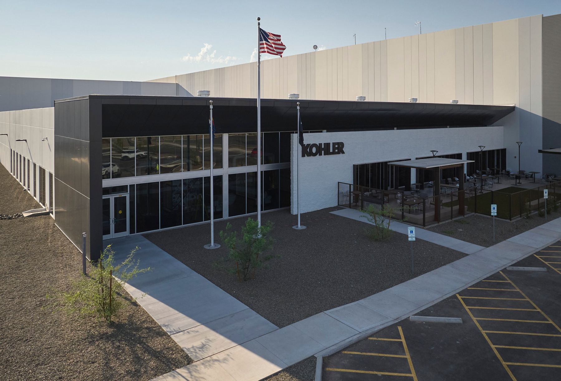 Modern Kohler building with American flag and clear blue sky.