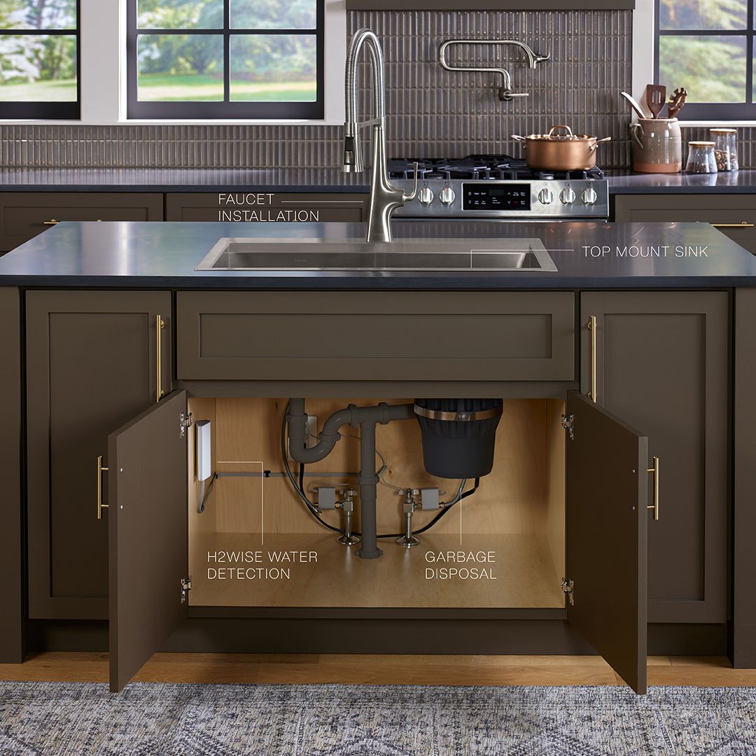 Kitchen sink with open cabinet below showing plumbing, 15% savings with three or more installation services.
