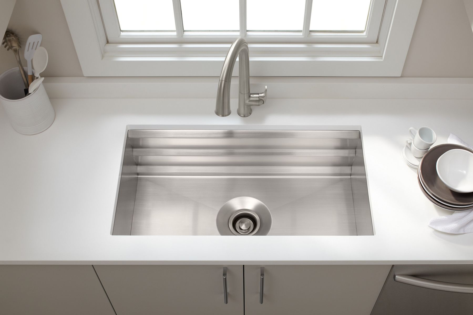 A view from above of a KOHLER Prolific stainless steel sink and a Sensate touchless faucet installed in a white countertop.