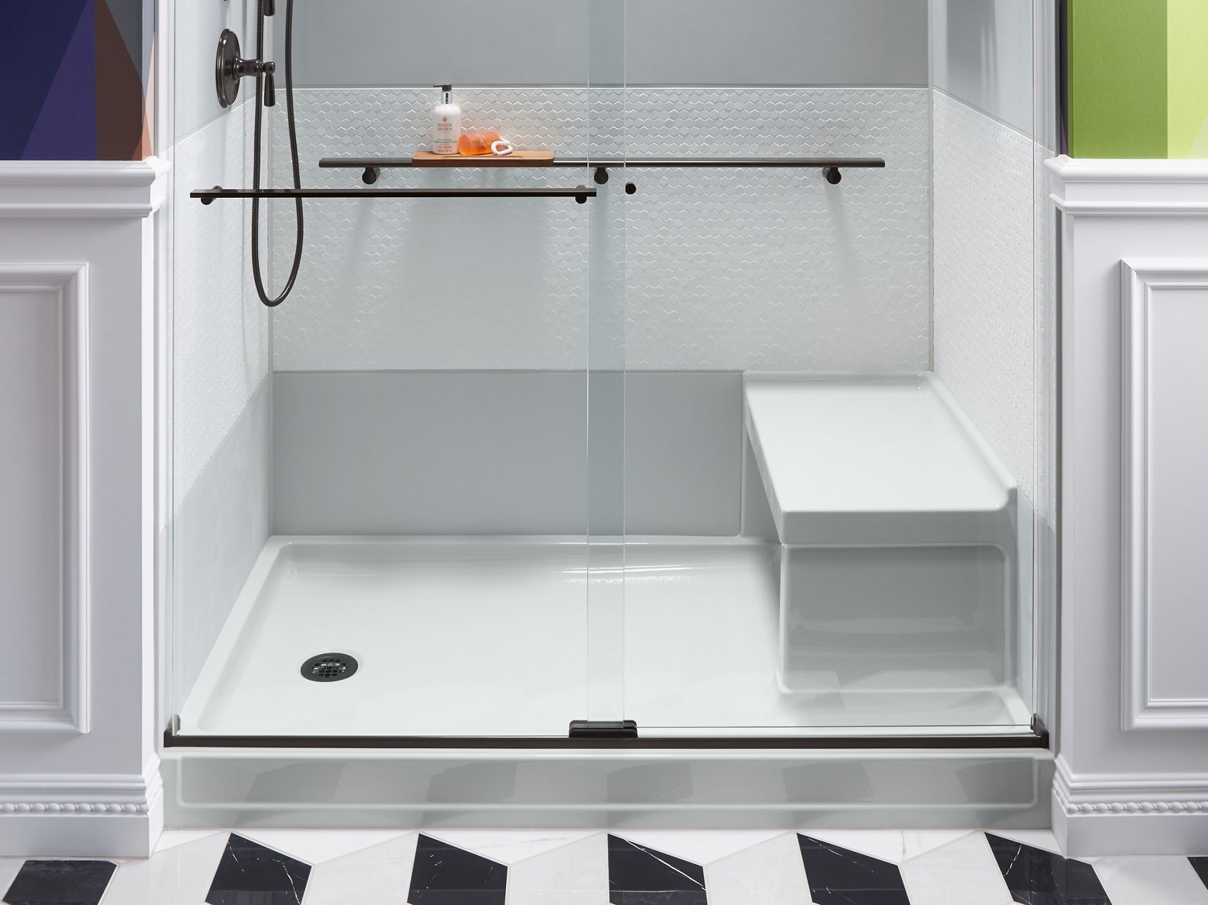 A close-up of a white acrylic shower base and show bench with sliding glass shower doors