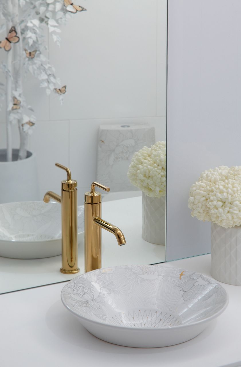 A round vessel bathroom sink with a surface design and a single control brushed brass faucet.