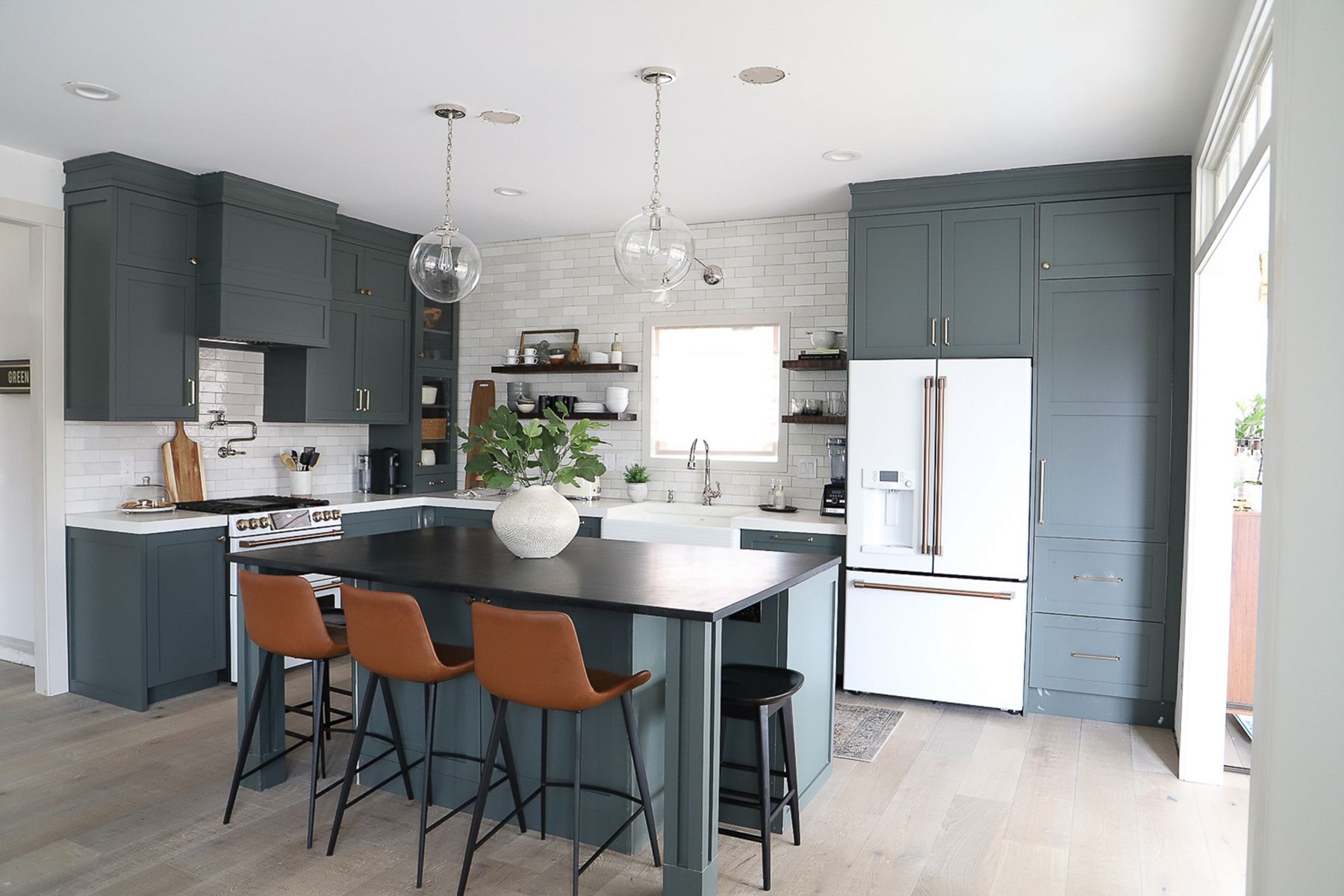 High contrast kitchen with island, green cabinetry, and KOHLER apron-front Whitehaven sink