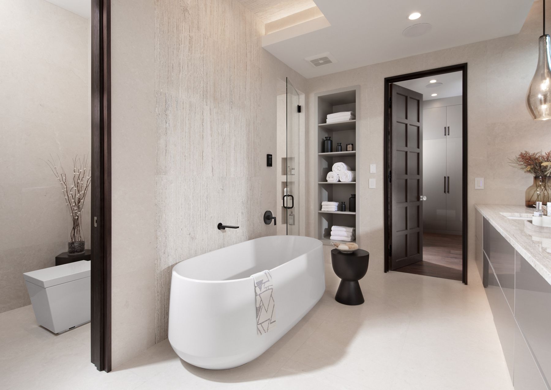 Transitional bathroom of The New American Home with Kohler freestanding bath and wall hung vanity with undermount sinks featuring a Numi intelligent toilet and large shower enclosure with digital showering system.