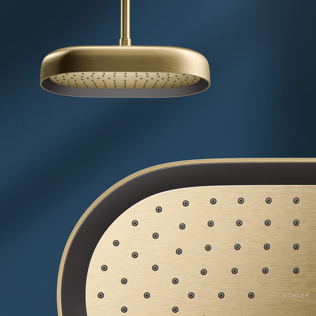 Une pomme de douche à effet de pluie oblongue Statement de KOHLER au fini Vibrant Brushed Brass dans une douche bleue, avec une vue détaillée des buses d’eau