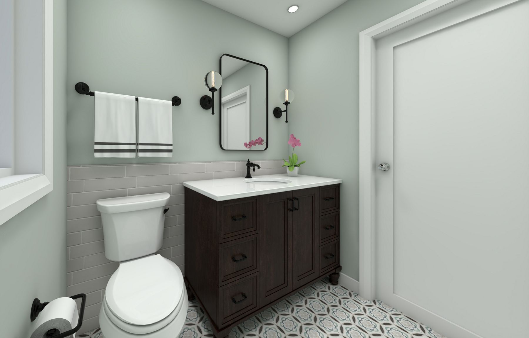 A bathroom with sea foam green walls, a toilet on the left, a dark wood vanity with white top on the right, and a patterned tile floor.