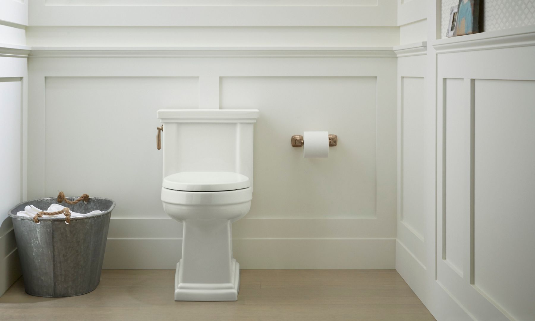A traditional toilet with square detailing against a white framed wall.
