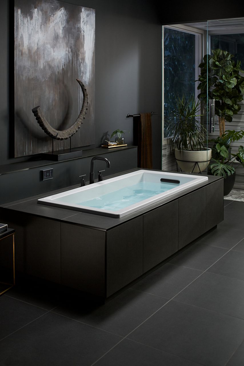 KOHLER whirlpool bath with black faucet in dark and moody bathroom