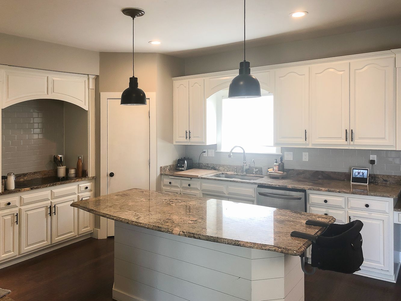 Older kitchen in neutrals with marble countertop and pendant lights