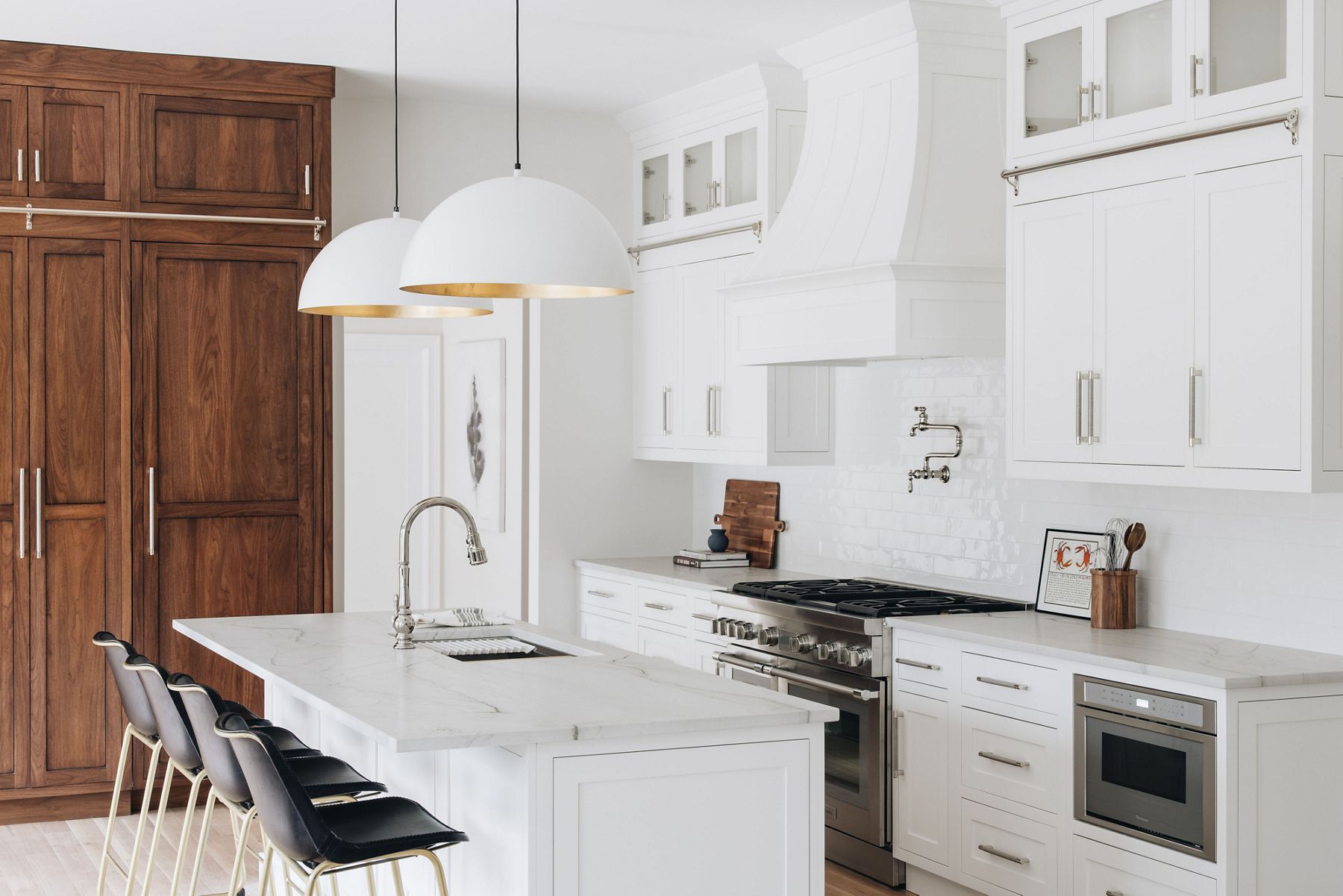 A kitchen with a white walls, cabinets, and island with a wood-grain cabinet to the side.