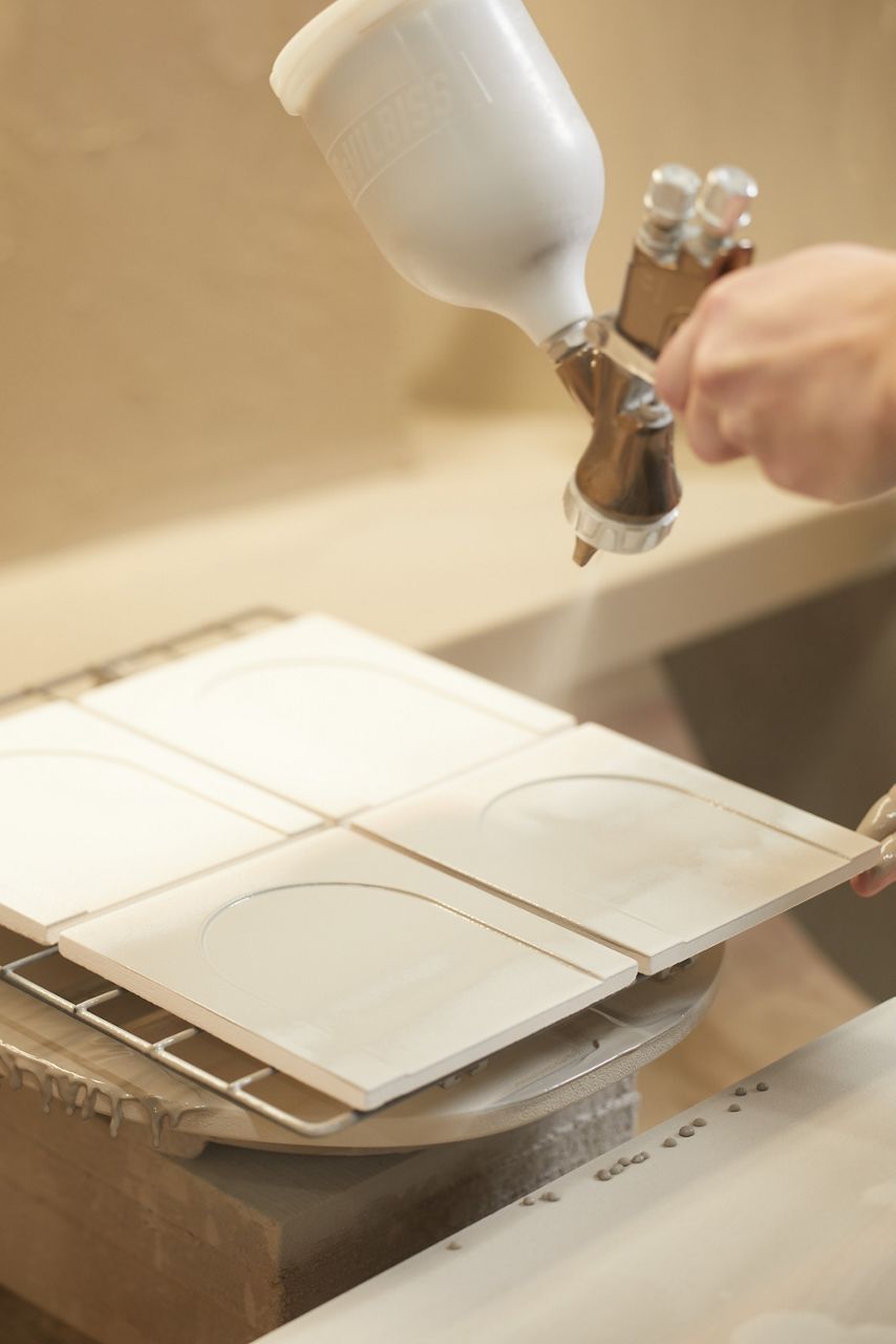 A close up of a person spraying bone finish tile created from the KOHLER WasteLAB.