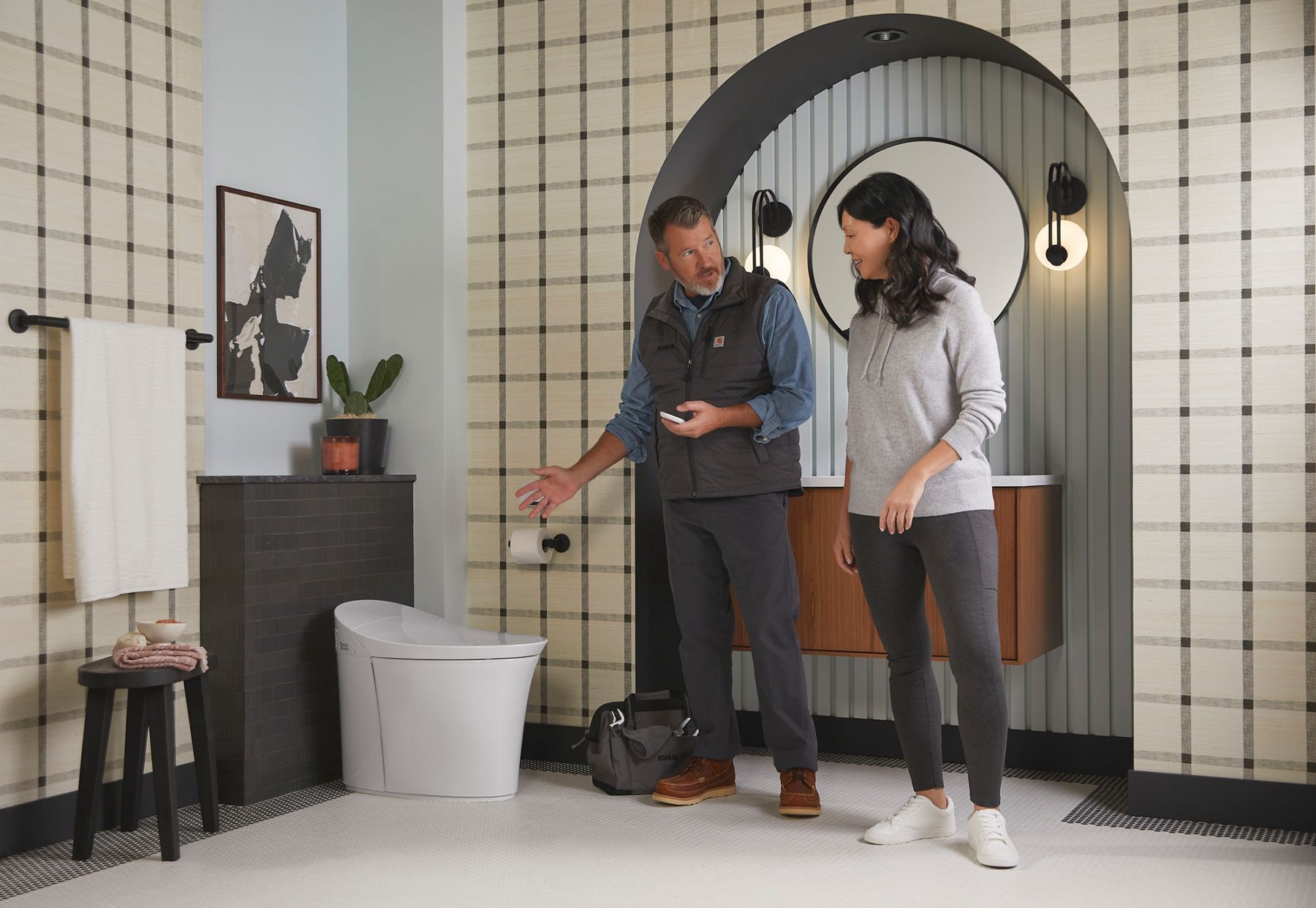 Two people in a modern bathroom discussing the installation of a smart toilet.