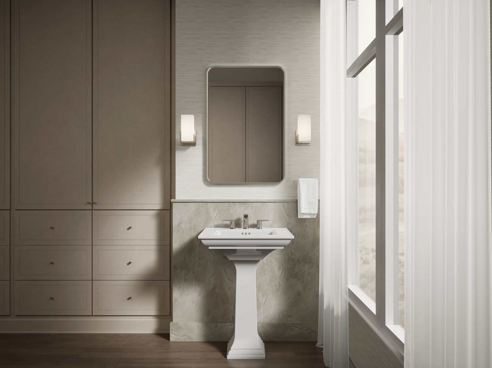 Claude collection pedestal sink showcased in a sophisticated bathroom with soft gray cabinetry, wall sconces, and large windows.