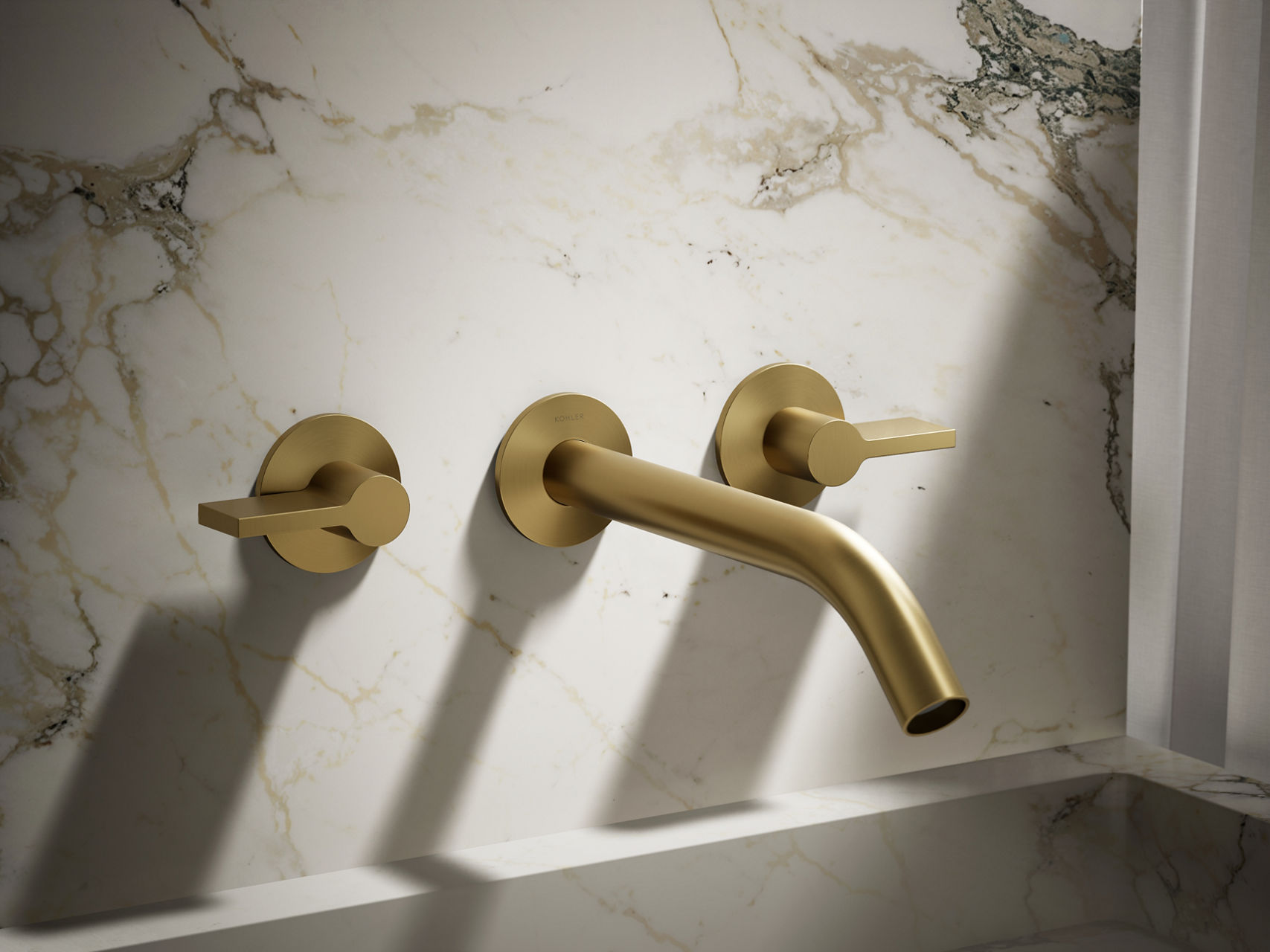 Wall-mounted brushed gold faucet with simple cylindrical handles and downward curved spout.