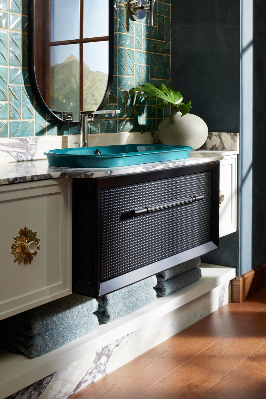 Modern teal rectangular sink with a built-in countertop on a black vanity, surrounded by green tiles and tropical decor.