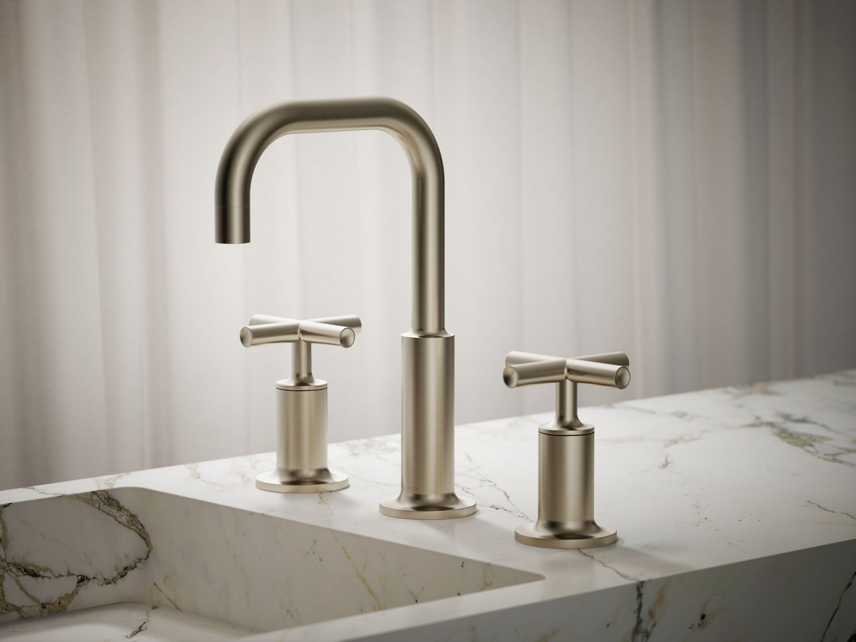 Brushed nickel widespread bathroom faucet with cross handles mounted on a white marble countertop.