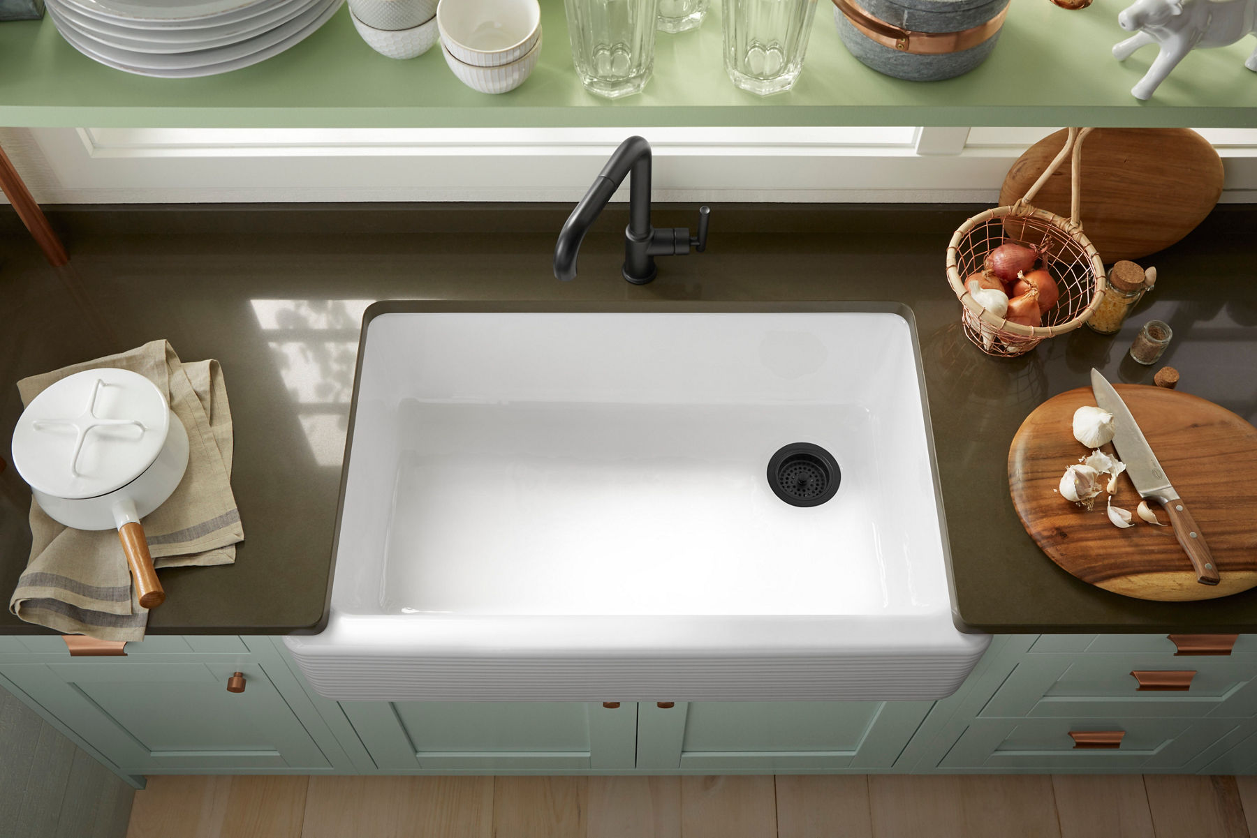 Traditional white apron-front sink on dark countertops paired with a center drain and vintage-style black forest.