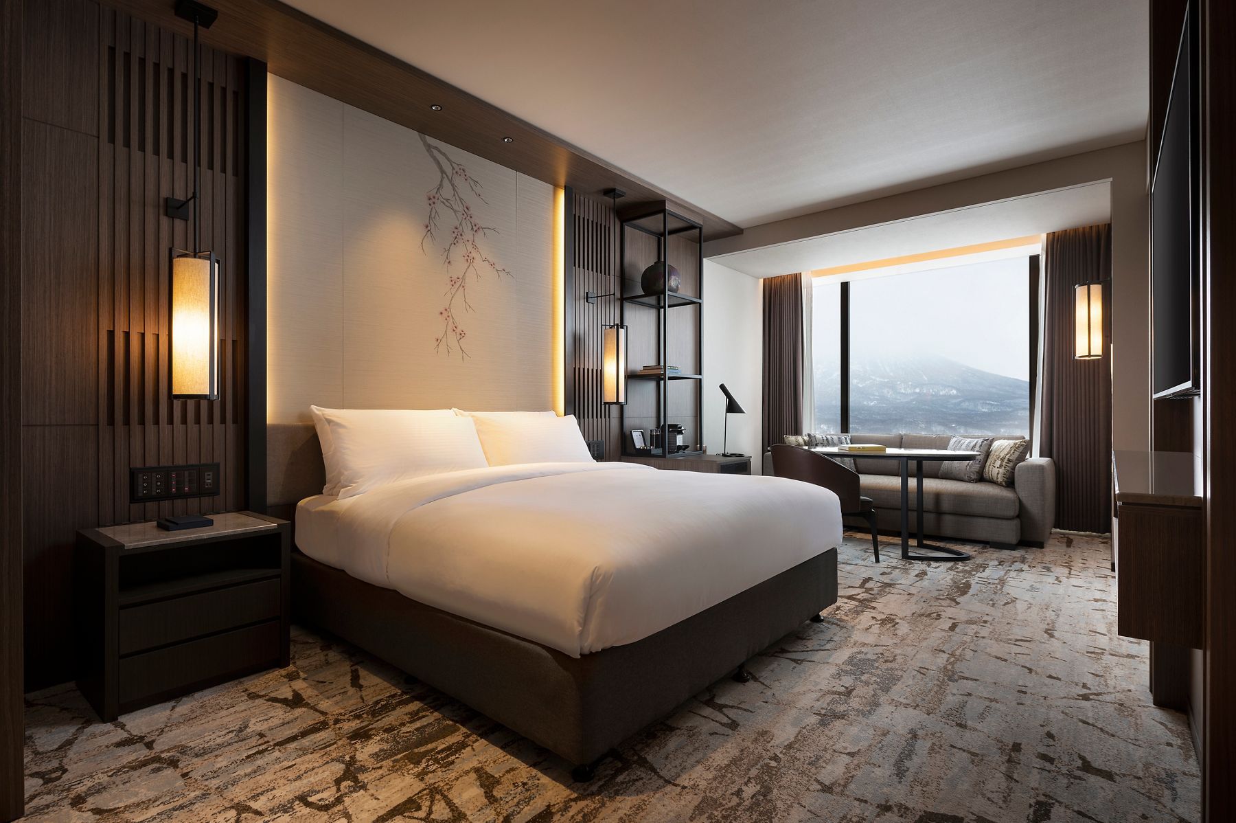 A hotel guest room with a mountain view, featuring a large bed and a sitting area.
