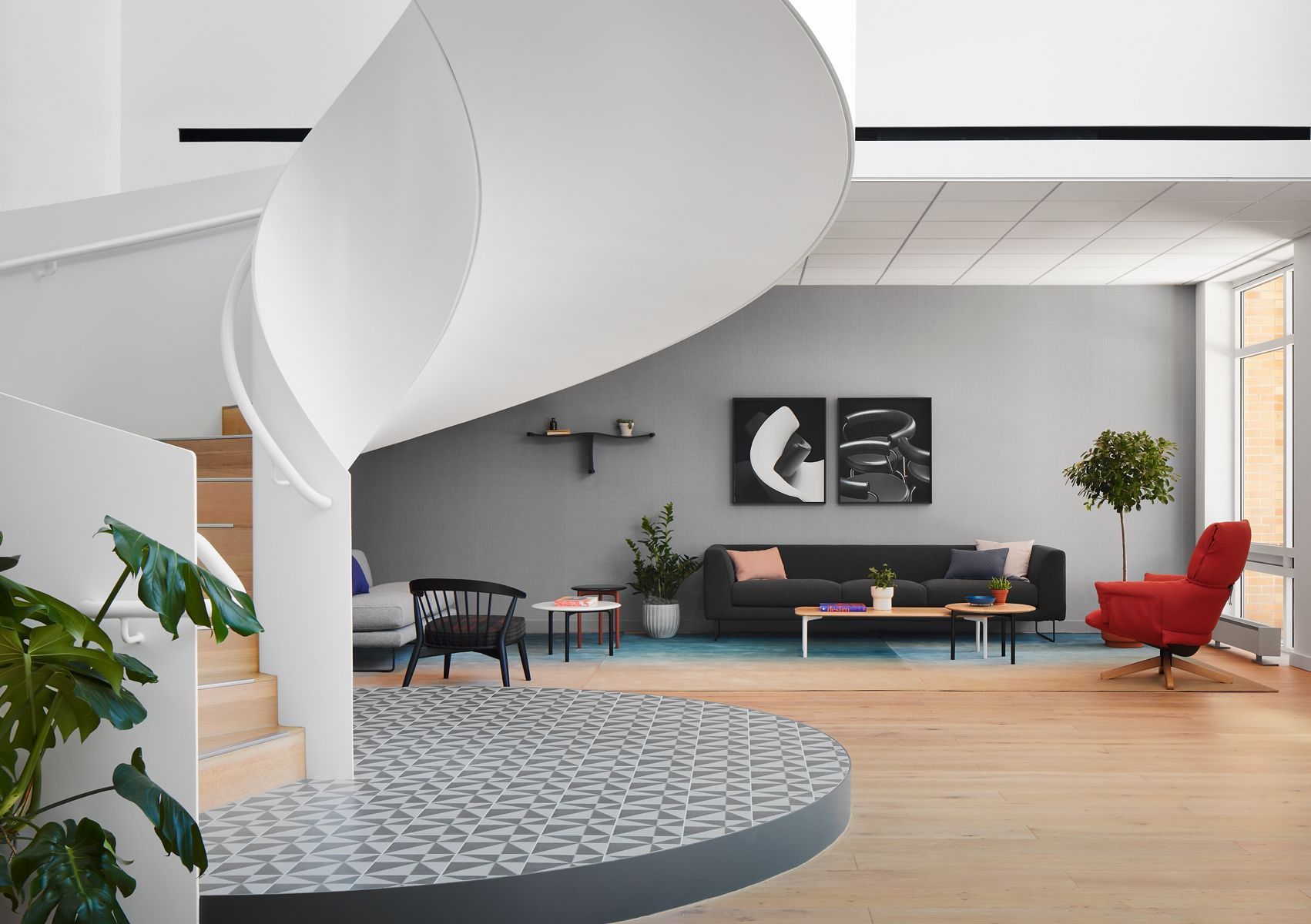 A lobby area at the Haworth Hotel featuring a red lounge chair and a grey couch surrounded by modern decor.