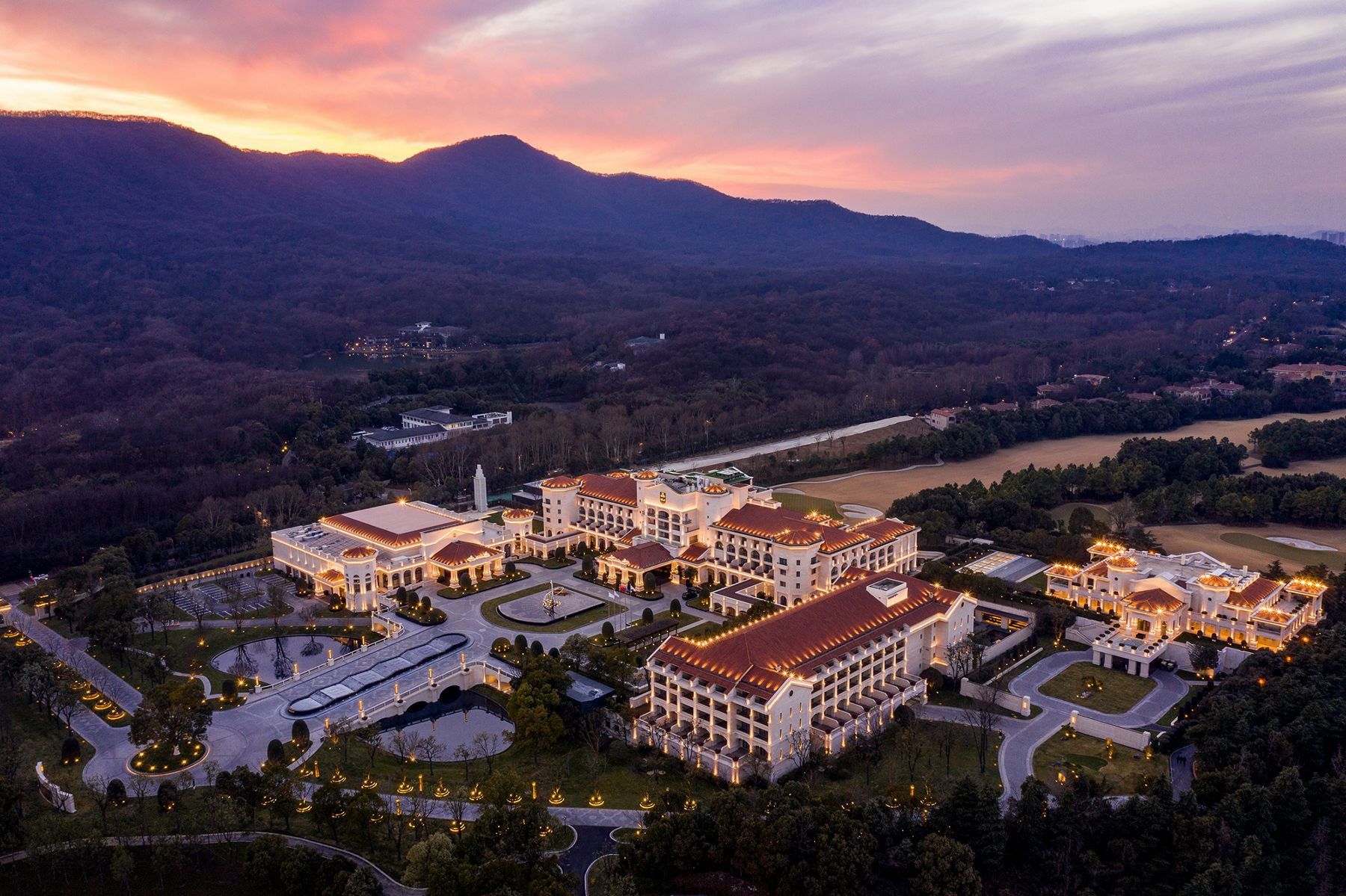 An aerial view of the Suning Zhongshan Golf Resort at sunrise, nestled in the foothills of the Zijin Mountains.