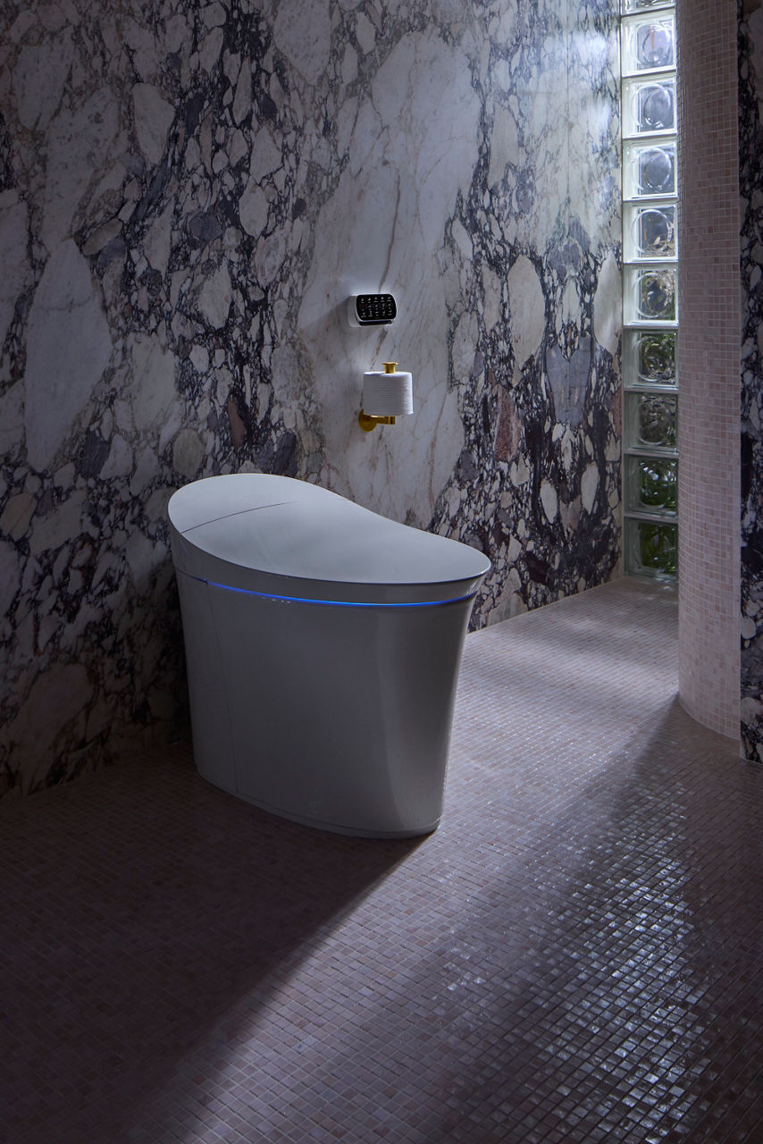 Modern bathroom with marble walls and glass blocks, featuring a smart toilet with integrated lighting.