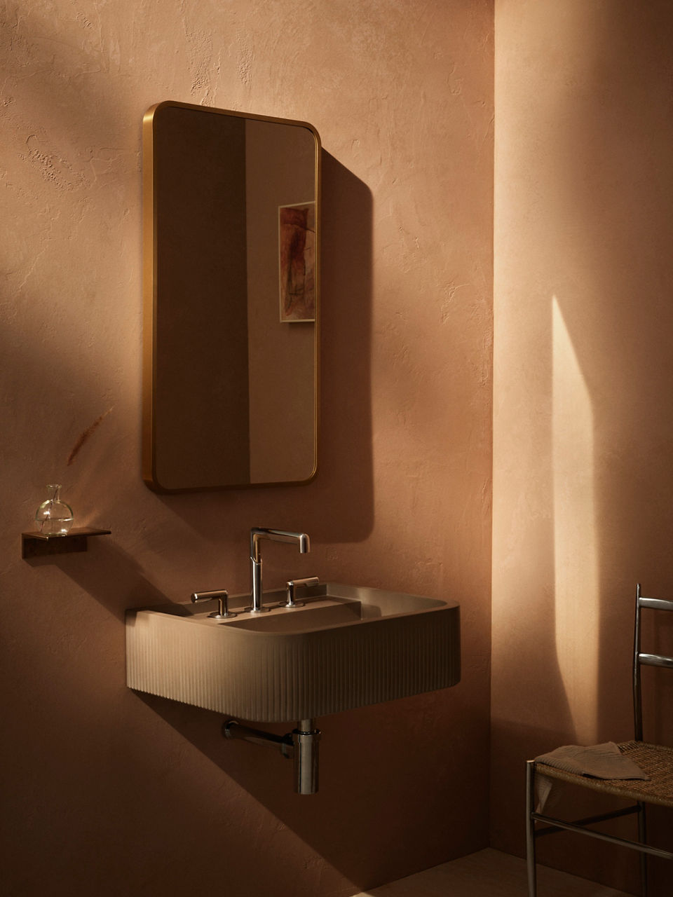 Illuminated mirror above wall-mounted sink with polished faucet