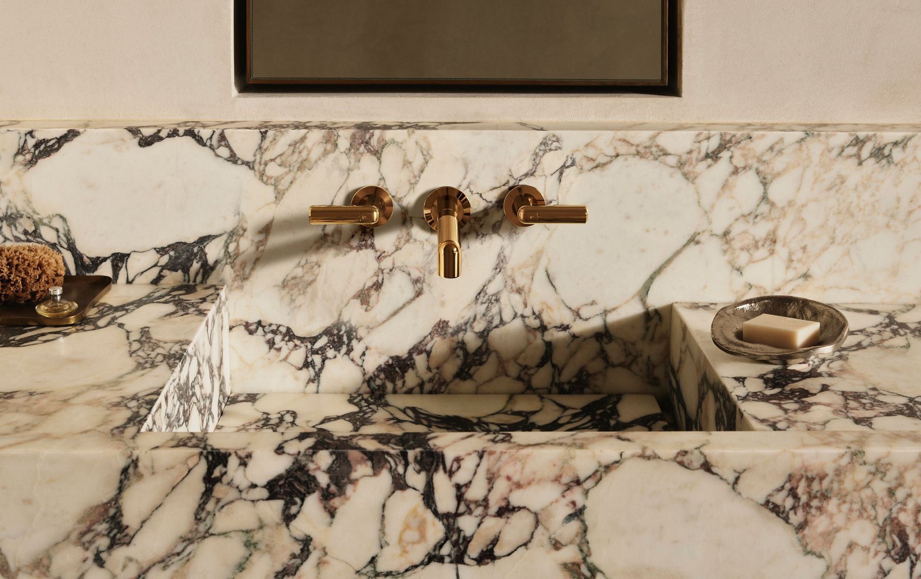 Vice wall-mount widespread faucet in Blush Brass above a Calacatta Viola marble sink and backsplash.