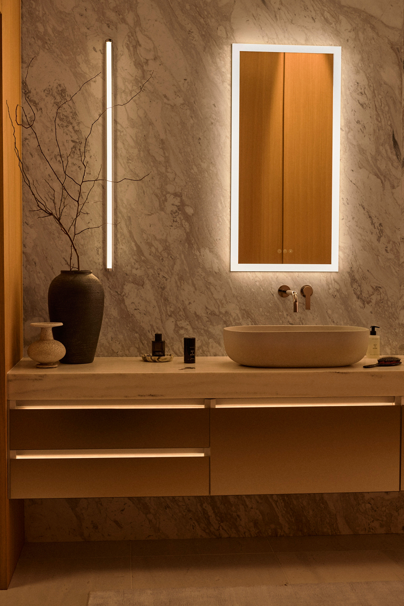 Wall-mount vanity with lit drawer edges and a stone vessel sink below a lighted mirror