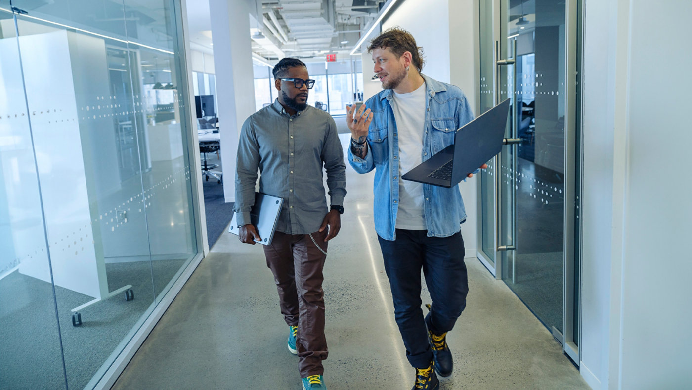 dudes walking in the hallway with laptops