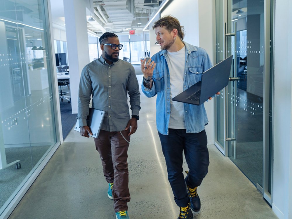dudes walking in the hallway with laptops