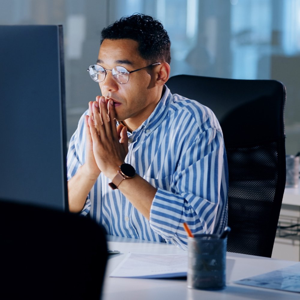 Man looking at computer monitor in an office - 21x9