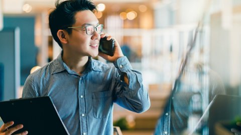 smart confidence asian startup entrepreneur business owner businessman smile hand use smartphone woking in office background