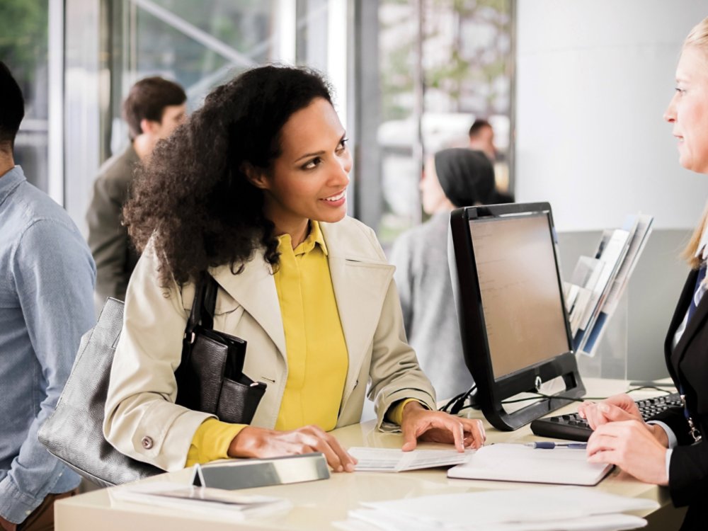 Female bank teller advising female customer for signing document.