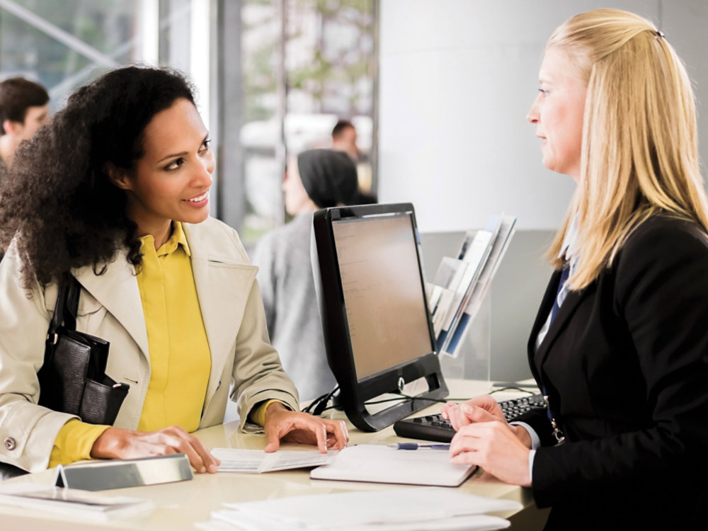 Female bank teller advising female customer for signing document.