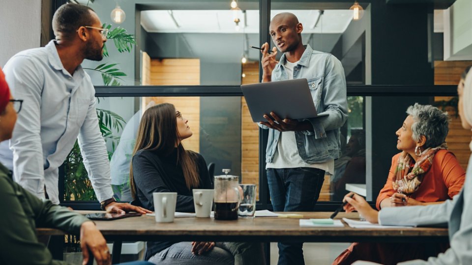 Diverse business professionals having a discussion during a meeting in a modern office. Team of multicultural businesspeople sharing creative ideas in an inclusive workplace.