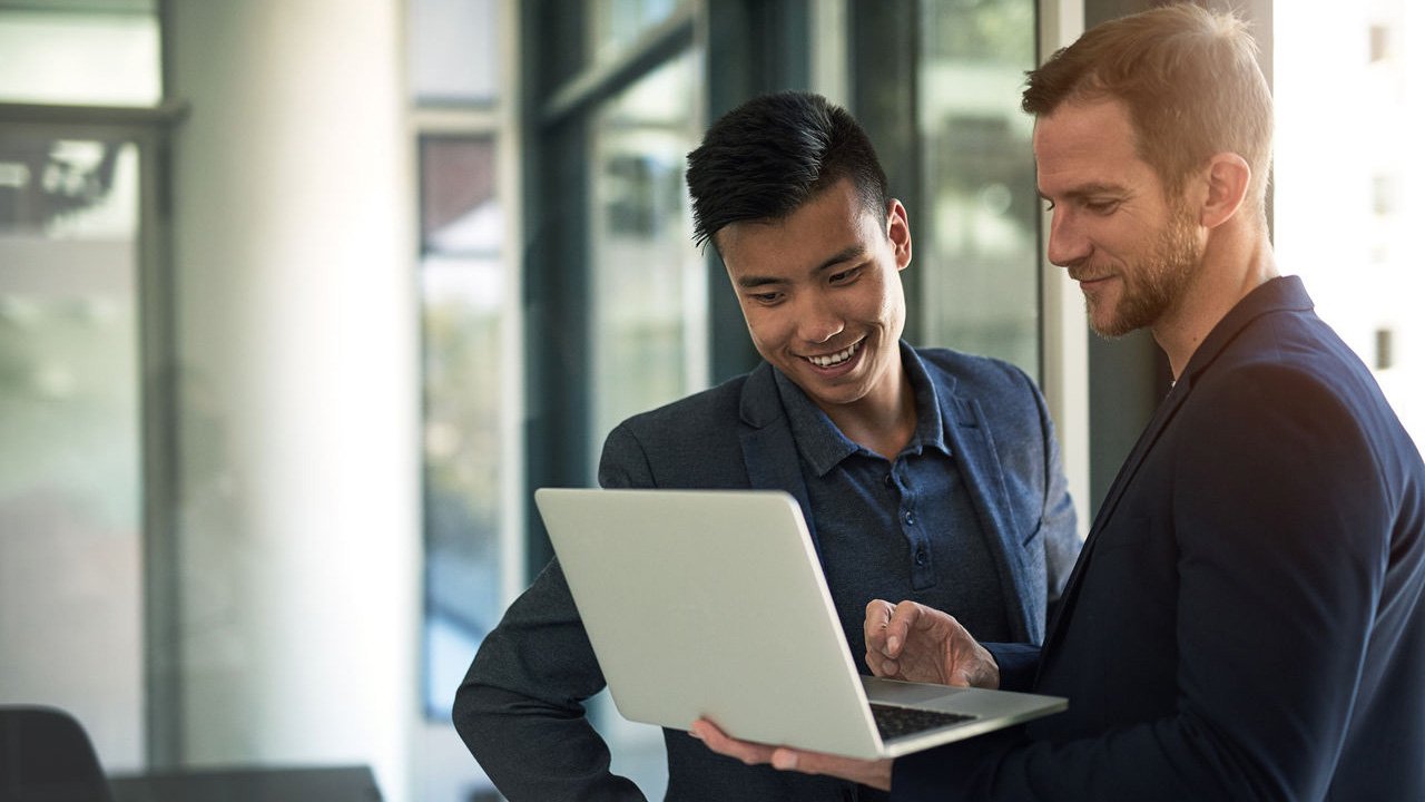 Shot of two businessmen discussing something on a laptop in an office