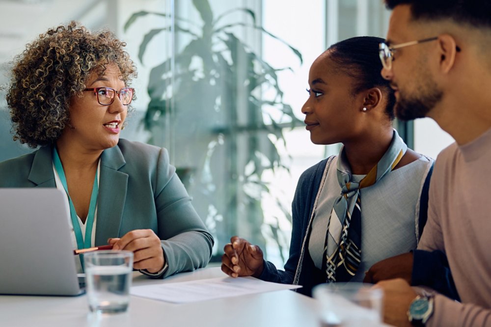 Financial advisor talking to young couple during meeting in office.