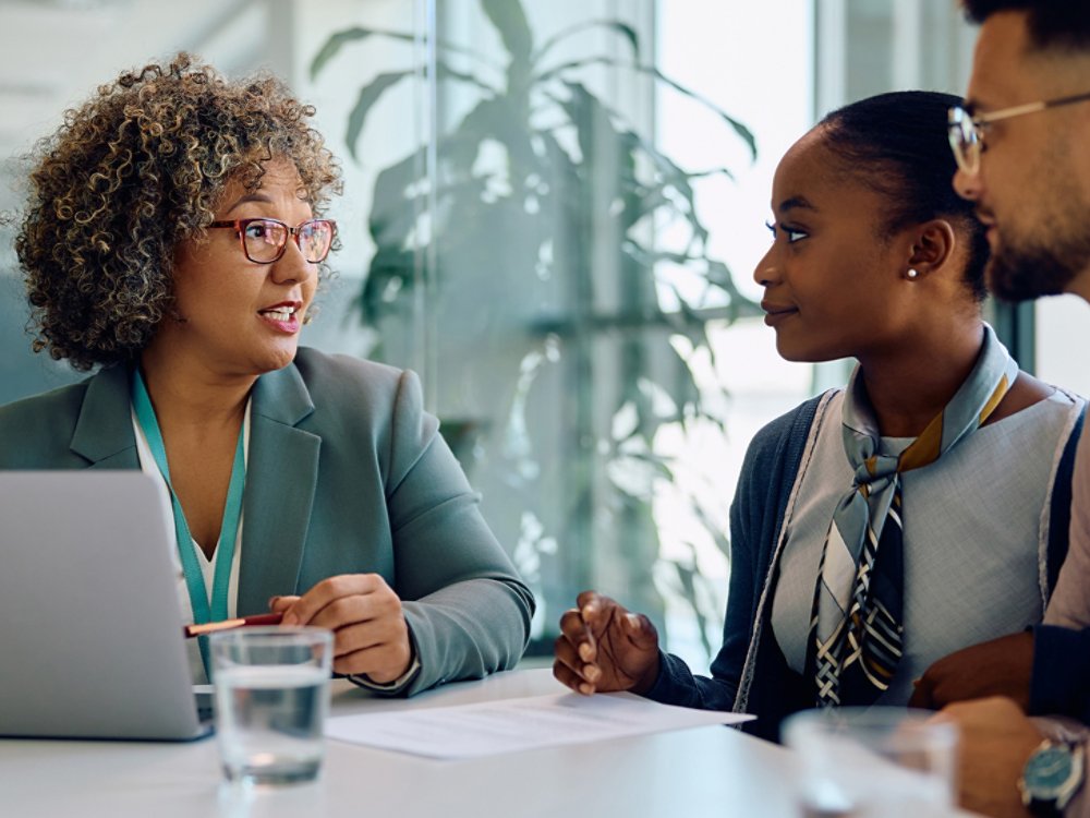 Financial advisor talking to young couple during meeting in office.