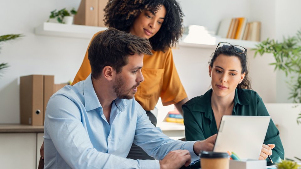 Three employees working at a computer together