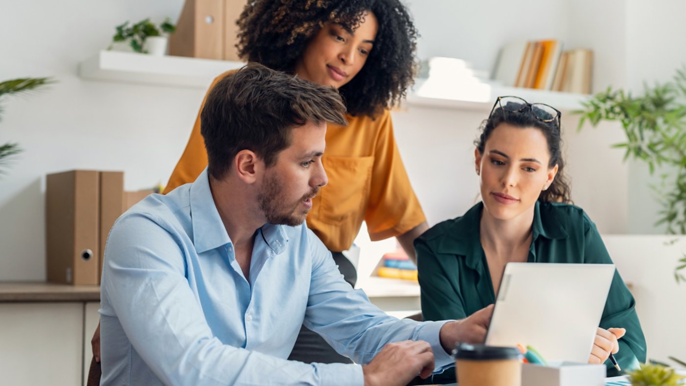Three employees working at a computer together