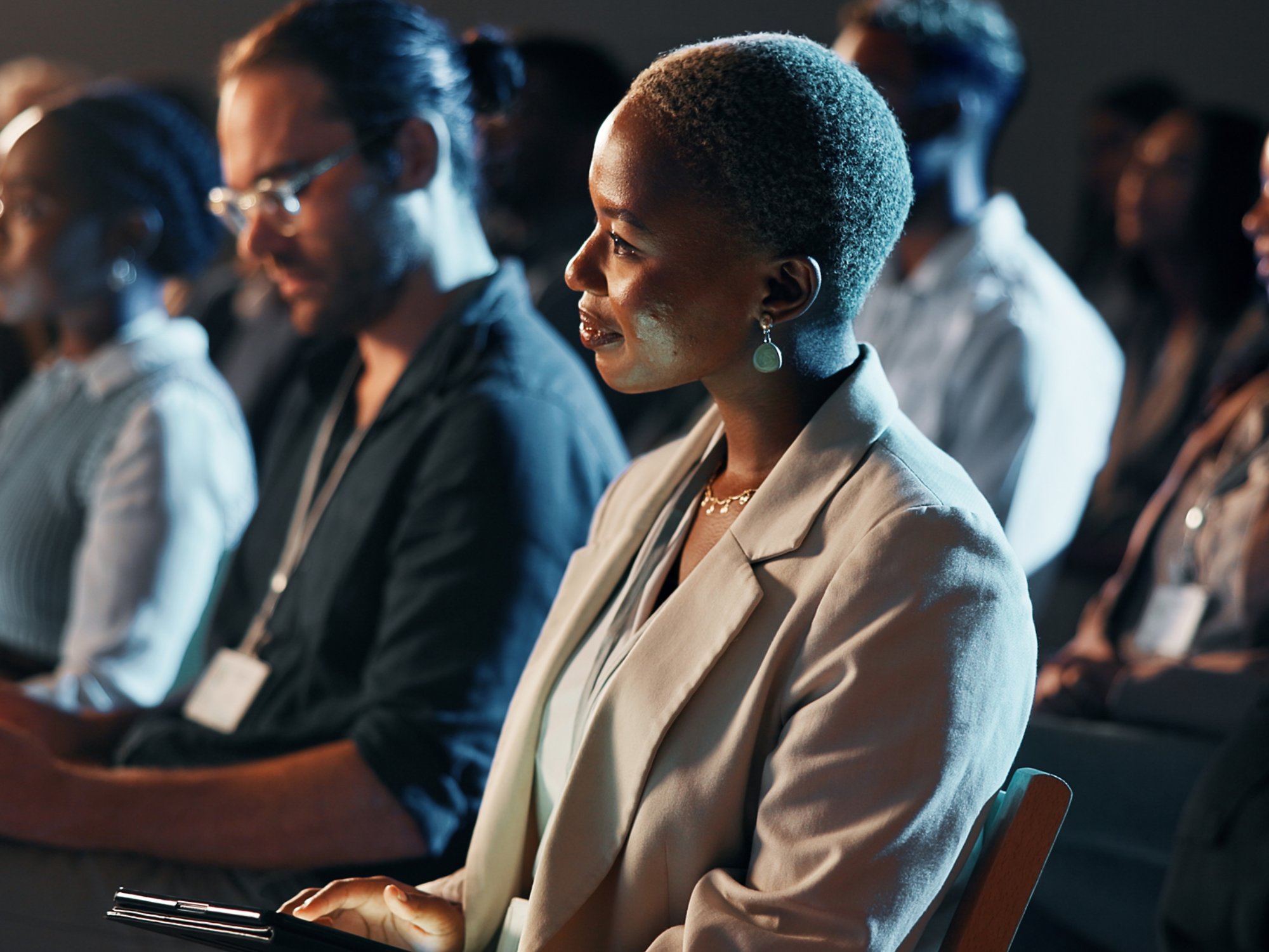 Listening, night and business woman at conference for tech seminar, app launch and quantum computing technology. Innovation, learning and workshop panel with people or audience at expo for ai forum.