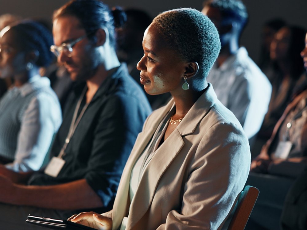 Listening, night and business woman at conference for tech seminar, app launch and quantum computing technology. Innovation, learning and workshop panel with people or audience at expo for ai forum.
