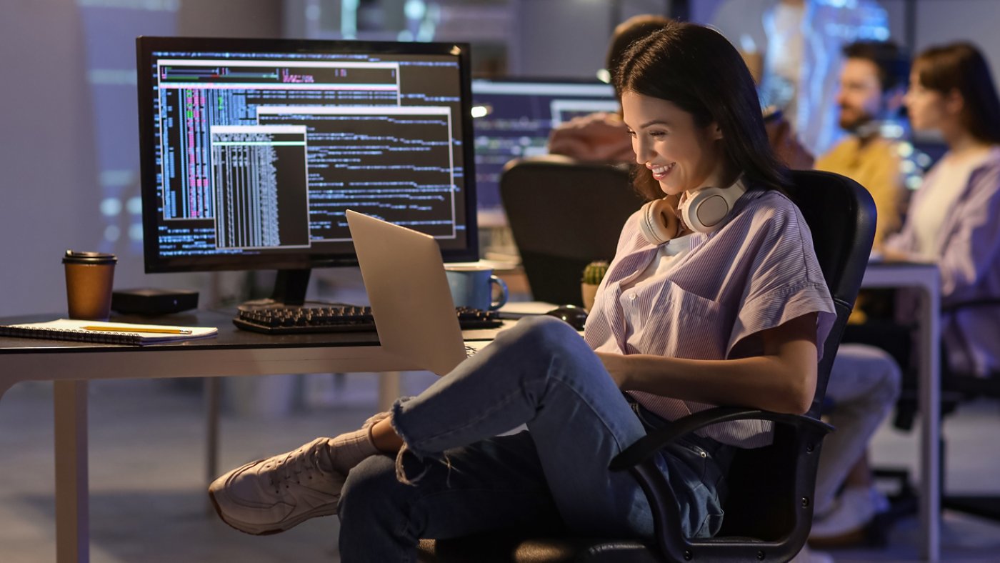 Female programmer working with laptop in office at night