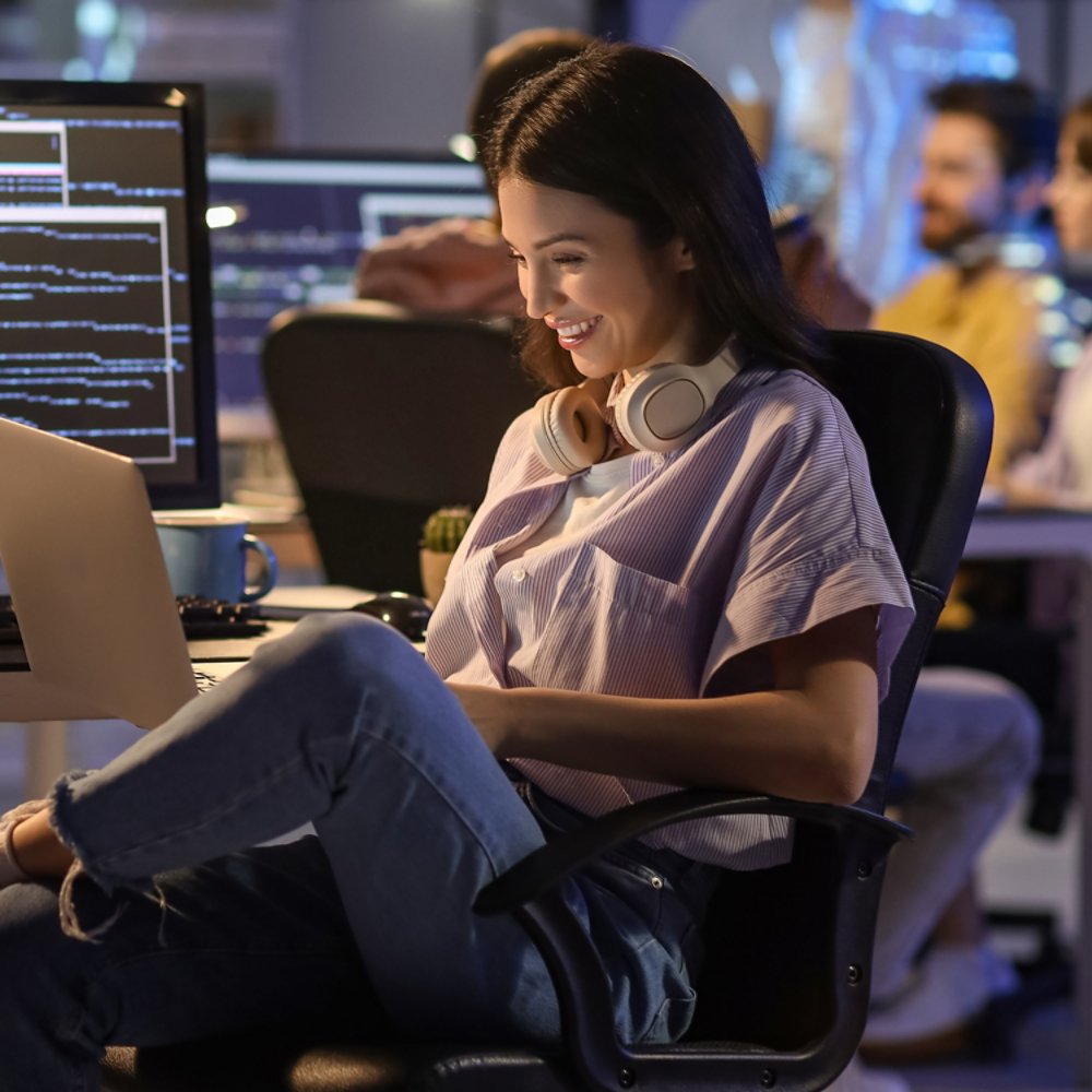 Female programmer working with laptop in office at night