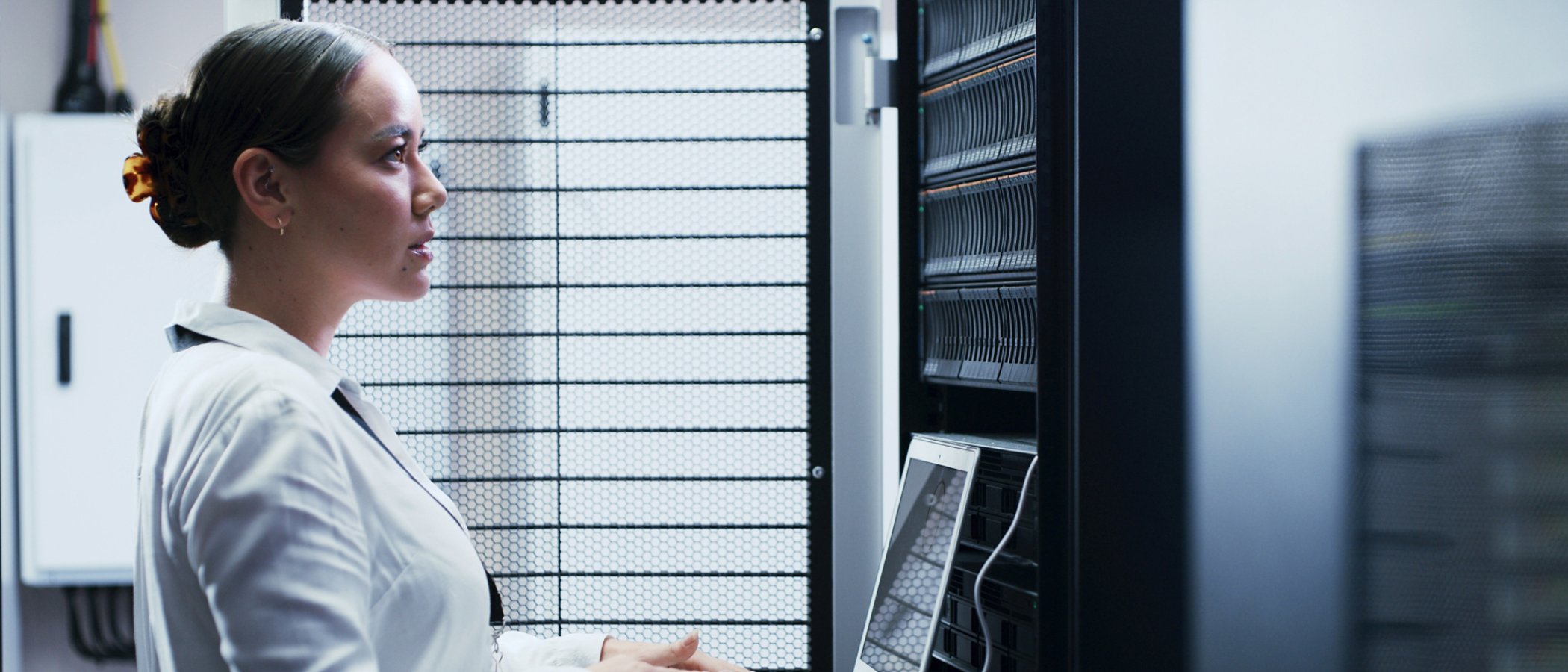 Laptop, typing and woman in server room for engineering, network maintenance or programming. Administration, computer and cybersecurity with IT professional in data center for firewall installation.