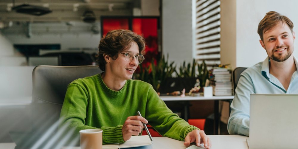 Business colleagues smiling and discussing ideas at office desk