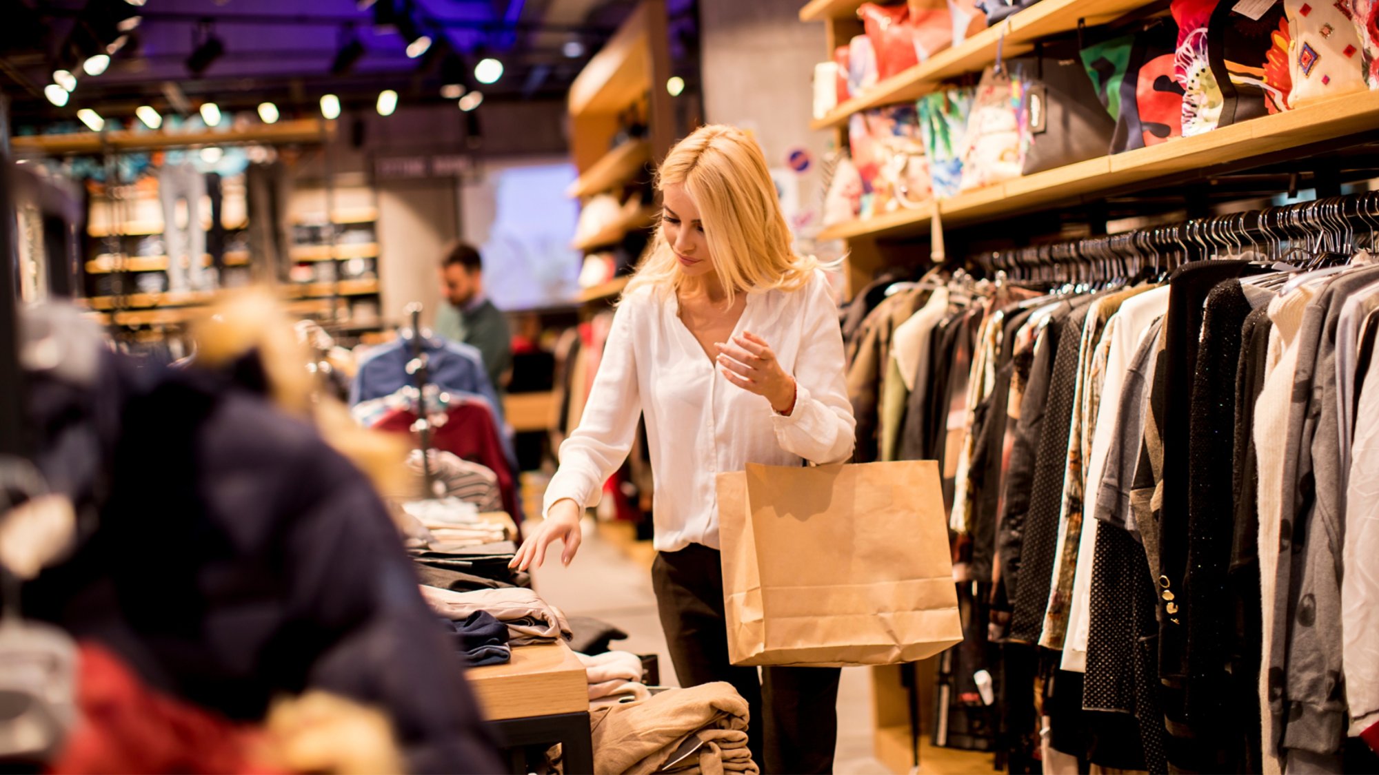 Beautiful young woman with shopping bags standing at the clothing store