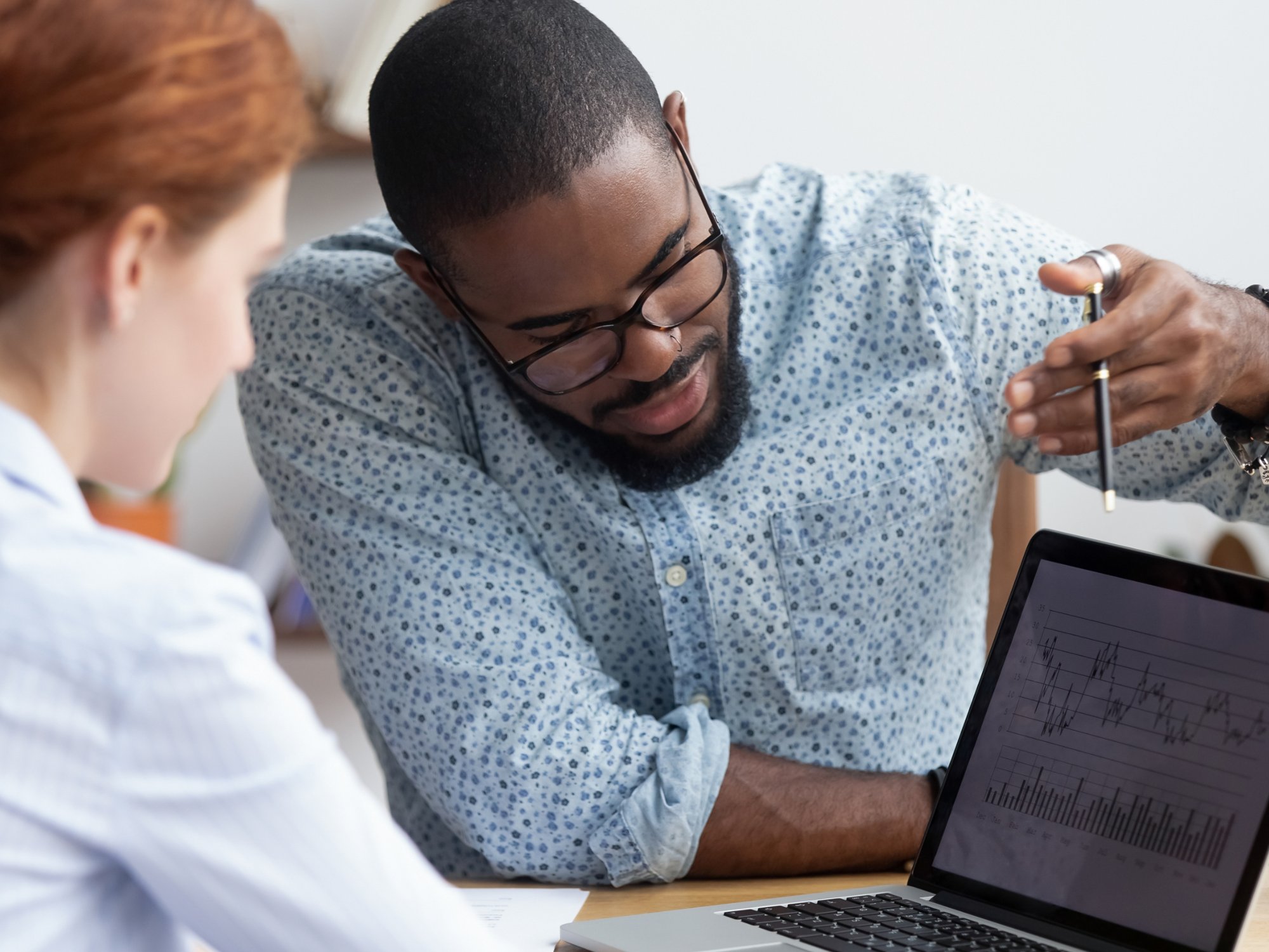 Colleagues working together analyzing data looking at laptop scr