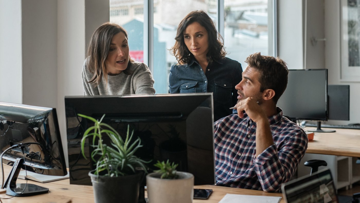 Diverse group of young designers working on a computer together